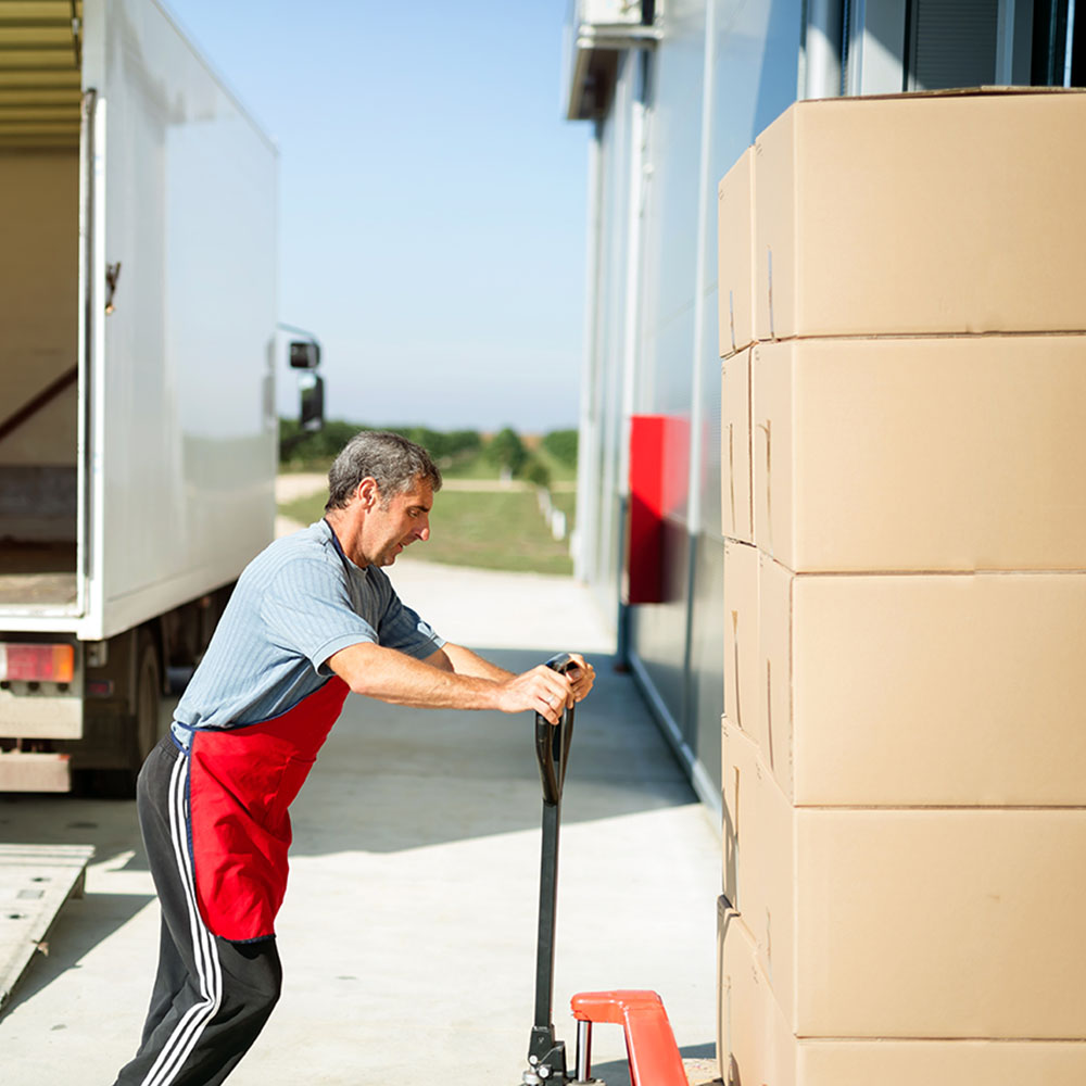 Logistics worker carrying delivered goods into warehouse
